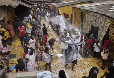 Ghanian men covered in white powder walking through a village street