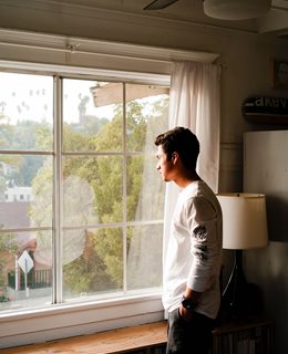 Young man standing by window