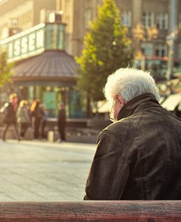 White-haired elderly man on a public bench in a town square (Huy Phan - Unsplash)