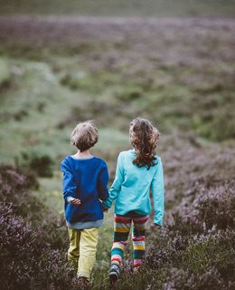 Children walking in a field hand-in-hand