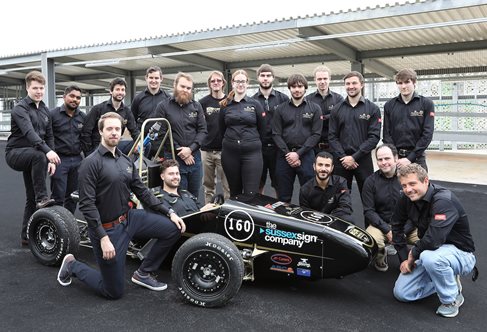 A group of people standing around the formula car