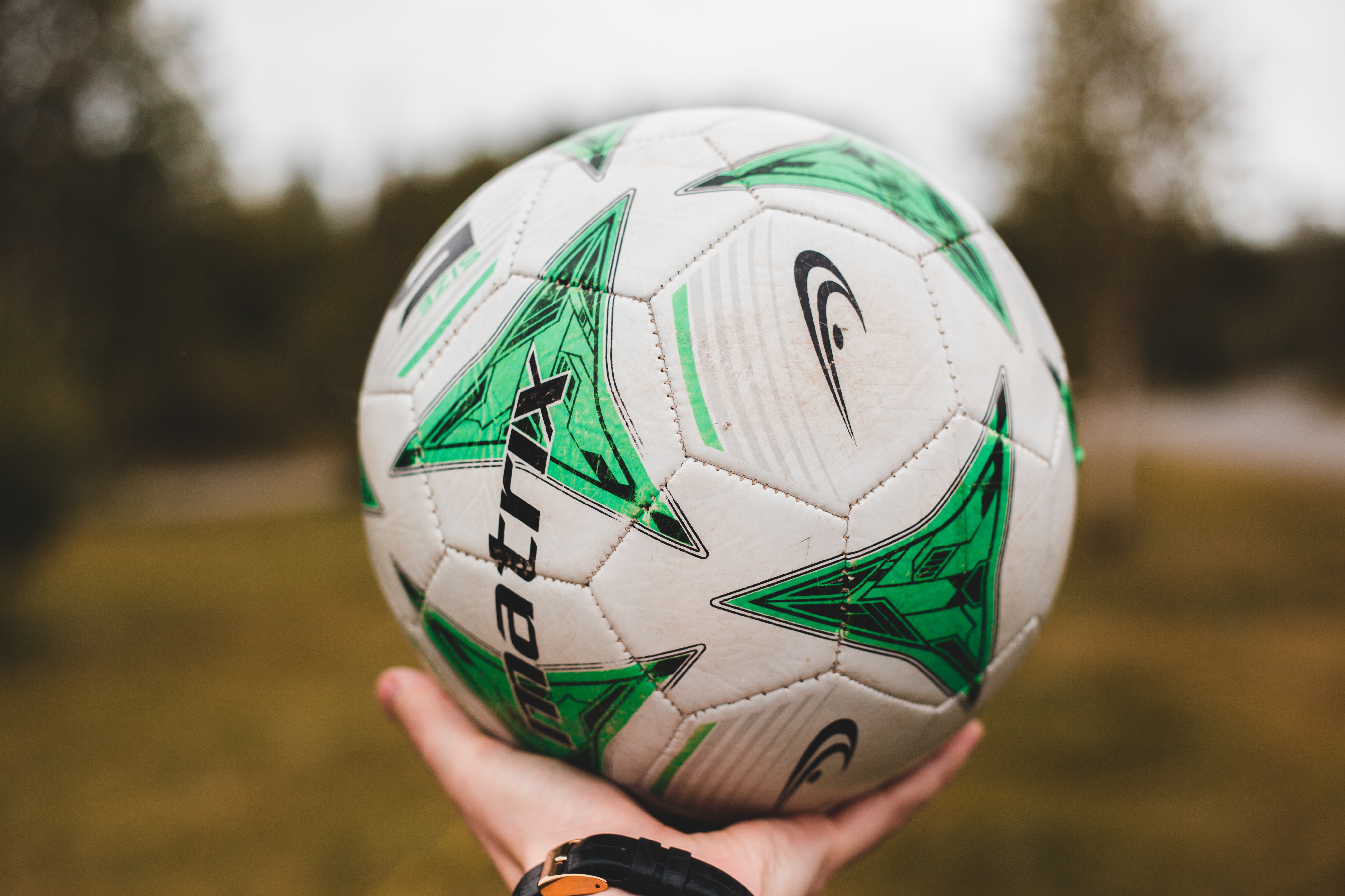 Hand holding a football, photo by Erik Mclean on Unsplash