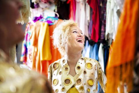 Alison Lapper in a gold jacket, looking sideways and laughing