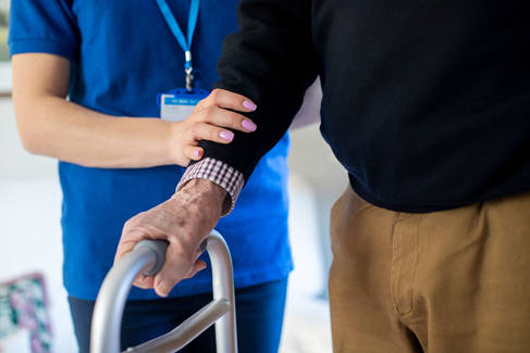 Elderly man being supported by care worker