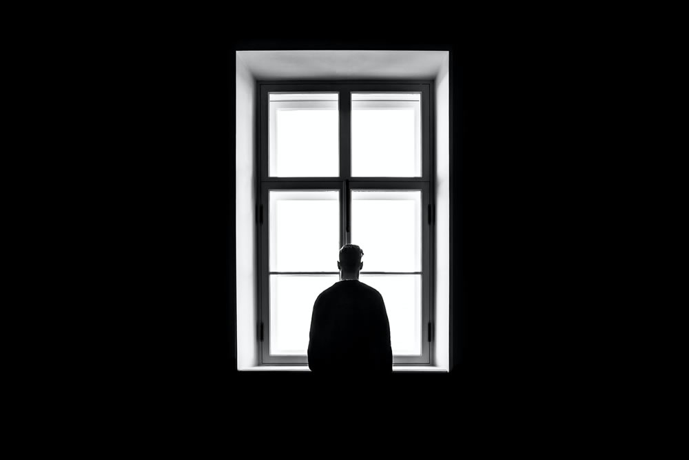 Man standing in front of a window in darkness