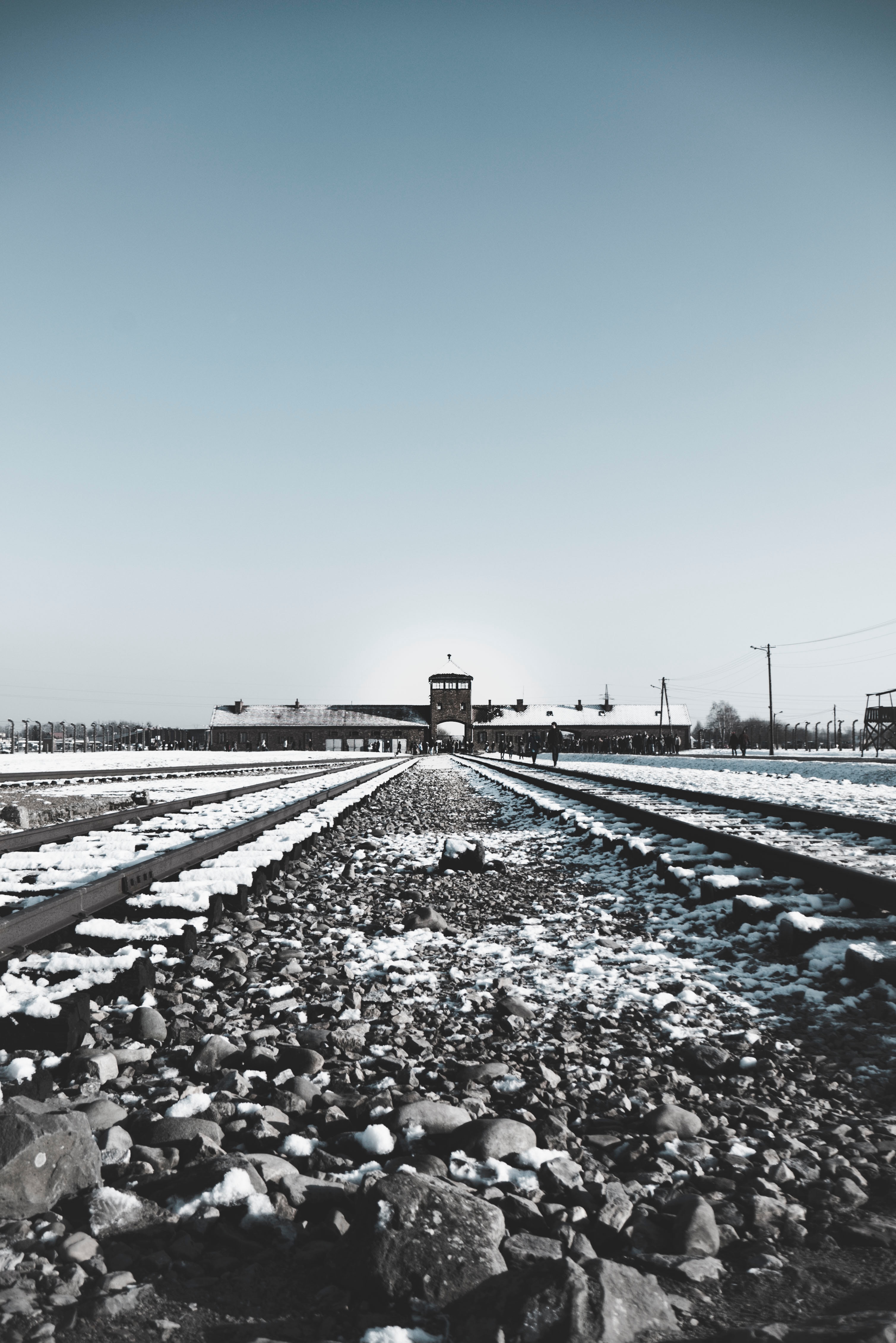 Snowy train tracks leading into a concentration camp in World War 2 Photo by Erica Magugliani on Unsplash