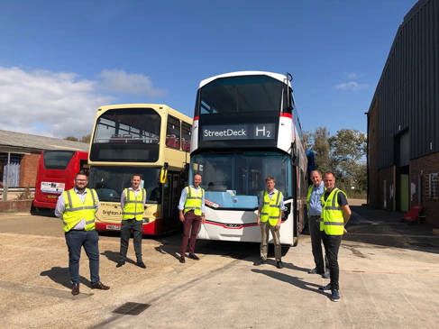 Six people in hi-viz vests in front of Brighton and Hove hydrogen bus H2