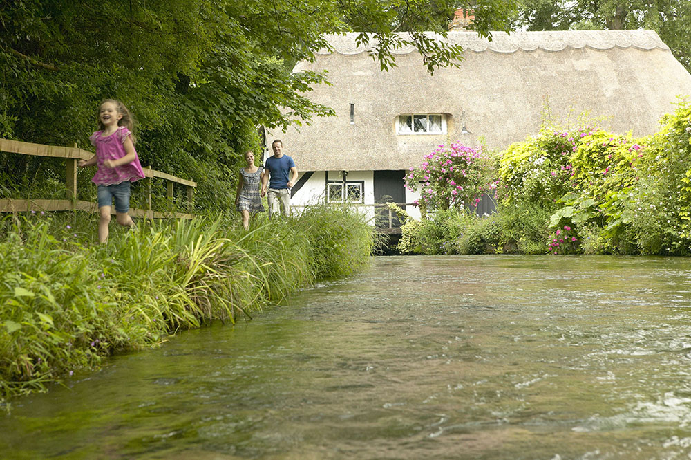 Family walking alongside river bank at Hampshire village of Alresford