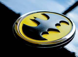 Traditional batman symbol of spread-winged bat with ears in black on yellow as a car badge. Courtesy Obi Pixel6propix from Unsplash