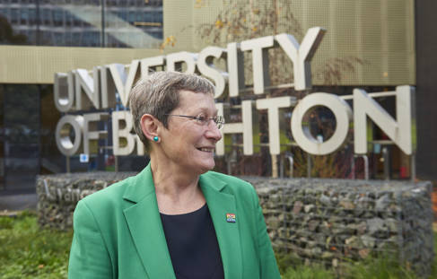 Professor Debra Humphris in front of the sign: University of Brighton