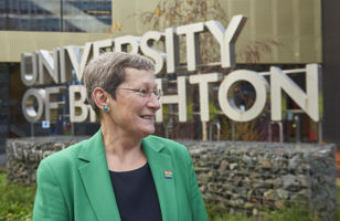 Professor Debra Humphris in front of the University of Brighton sign