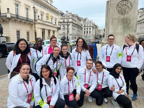 A group of people in white jackets with pink lanyards