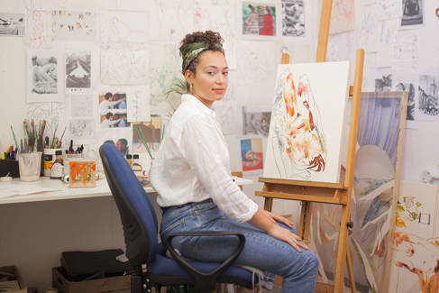 Artist sitting next to one of her paintings