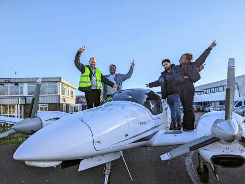 Four people standing on the wings of a plane