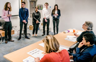 A group of students giving a presentation to a panel of judges 