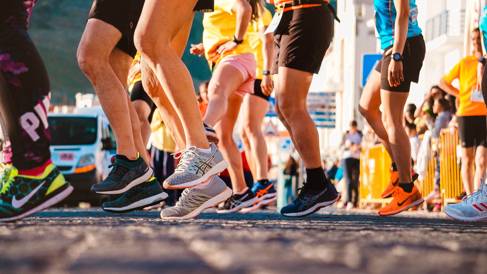 Runners legs and feet in trainers at the start of a marathon race. Image courtesy of Pexels and RUN 4 FFWPU