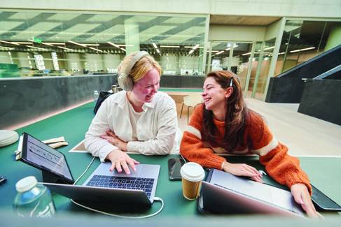 Two students working on a laptop in a shared space