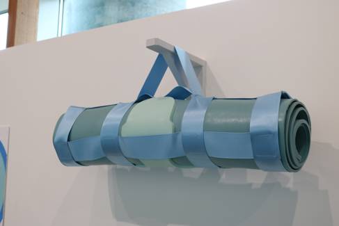 A blue body mat, rolled up and hanging on the wall