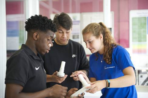 A female university student ambassador helps two young students