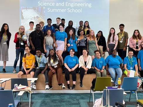 A large group of students all smiling for the camera in front of a sign reading 'Science and Engineering Summer School'