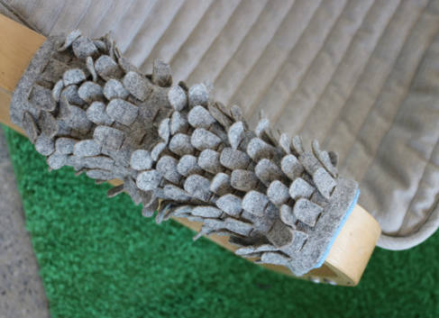 An arm of a chair covered in textured, grey material