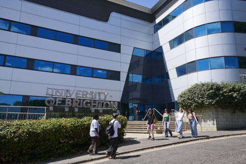 Modern white building with students stood in front of it.