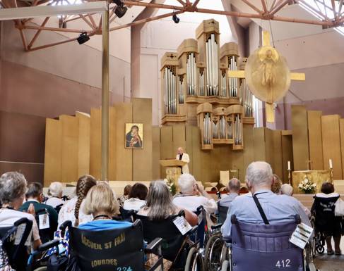 People in wheelchairs face an altar. You can't see their faces