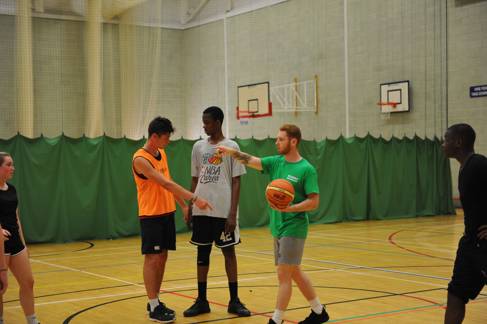 Students playing basketball in an indoor court