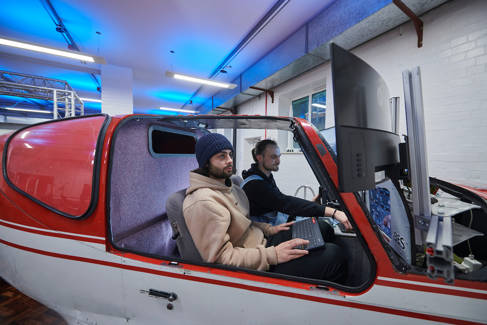 Two students using aerospace engineering simulation equipment in a model helicopter