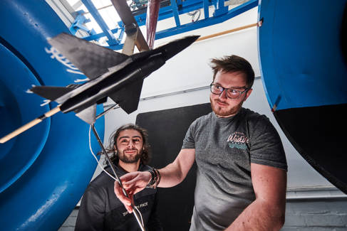 Two students working with a model aeroplane in a wind tunnel 