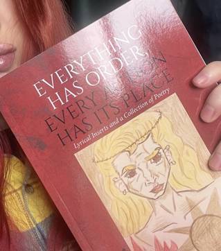 Wren holding up  Everything Has Order, Every Action Has Its Place Lyrical Inserts and a Collection of Poetry