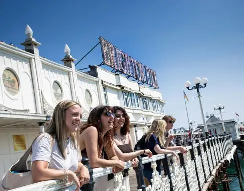 Young university students smile while on Brighton Pier