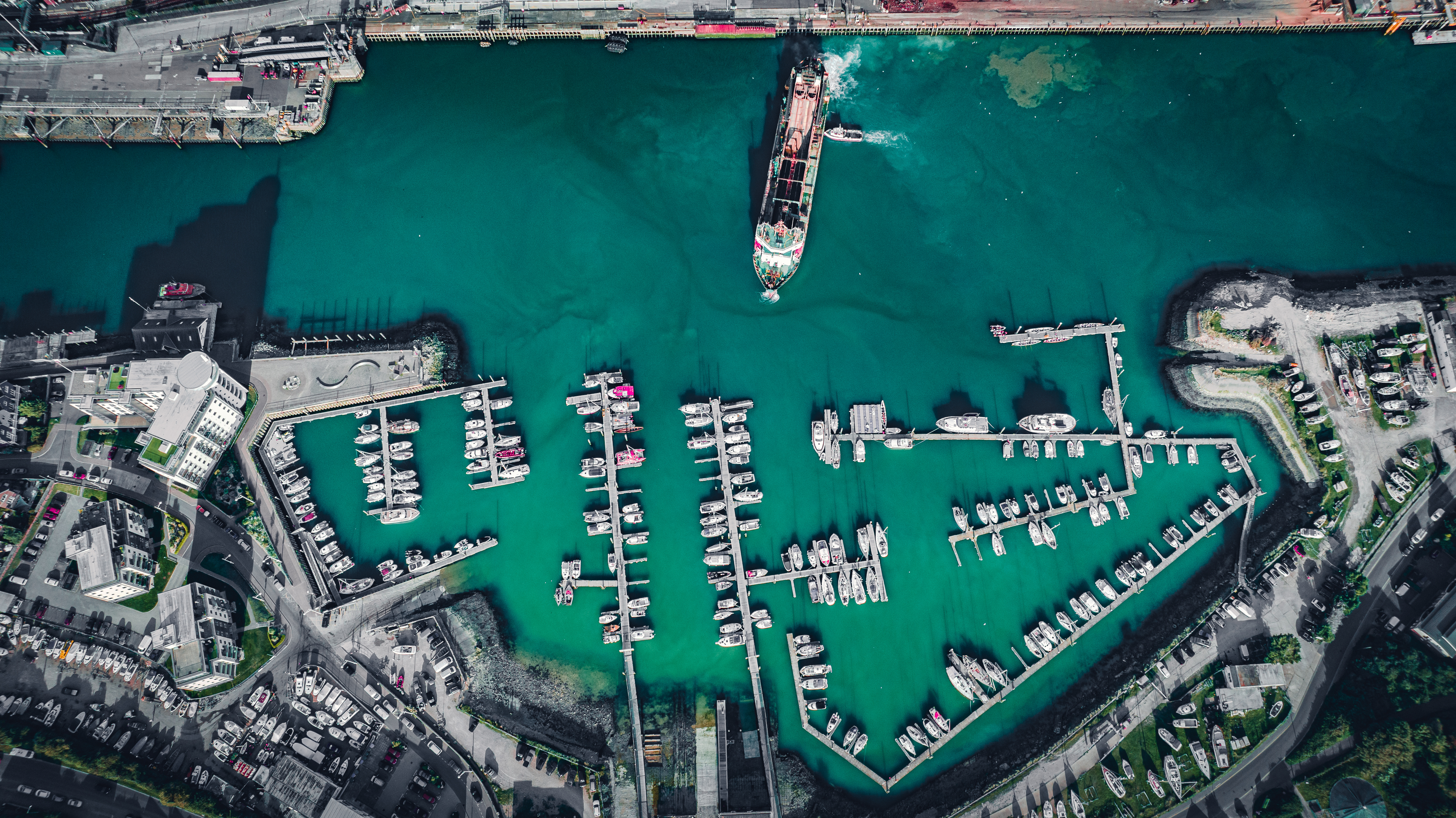 An aerial shot of a shipping port. Blue waters and boats on the water.
