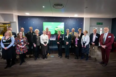 A large group of senior leaders and executives smile at the camera