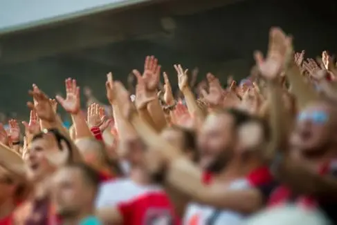 A sea of football fans have their arms in the air