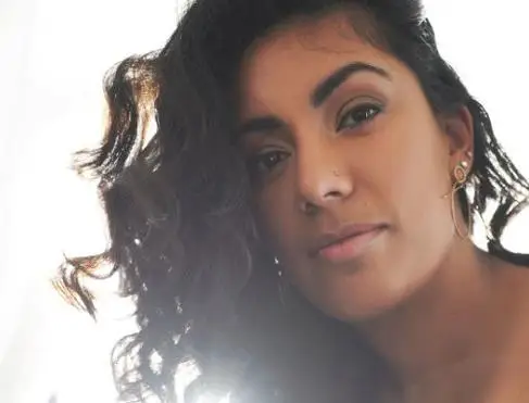 A selfie of a young South Asian woman with dark curly hair