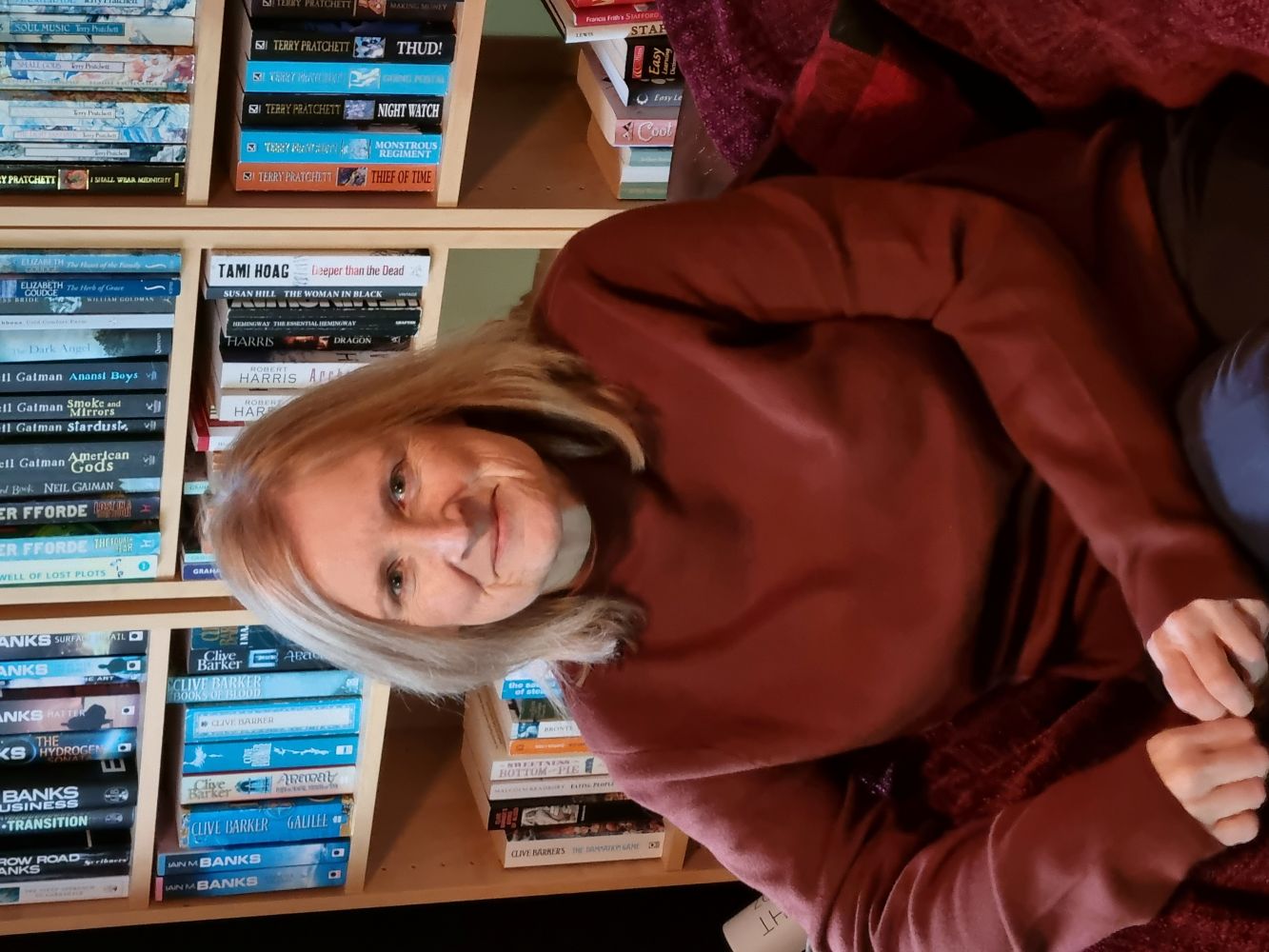 A white woman smiles in front of bookshelves