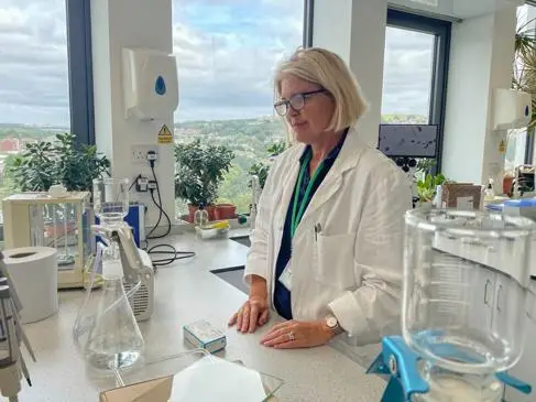 A woman with a white bob analyses microplastics in a lab