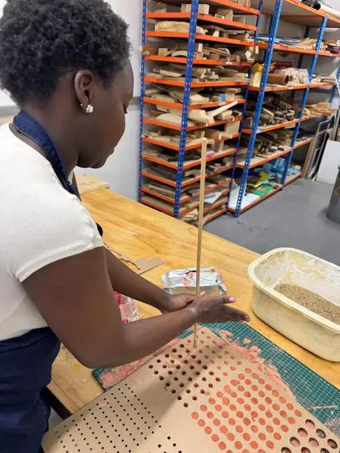 A young Black woman works with clay in a studio