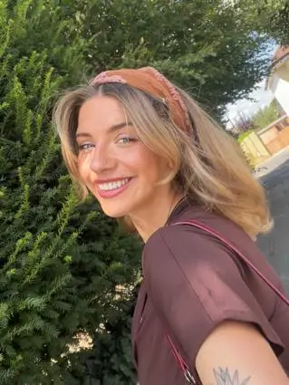 A young blonde woman wearing a bandana takes a selfie smiling