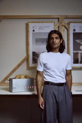 A young man stands next to a toaster he's designed