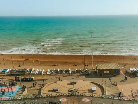 An aerial shot of Brighton beach, with people on the seafront and in the sea
