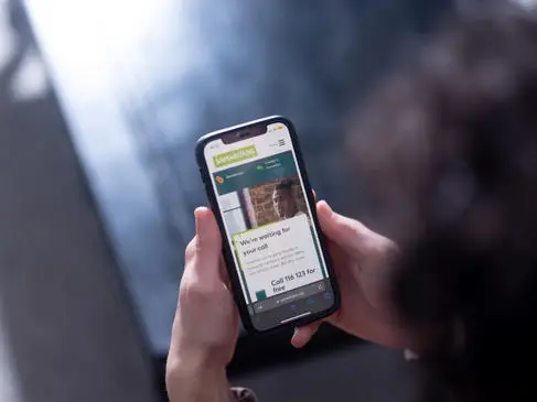 Hands holding a phone that shows the Samaritans helpline number