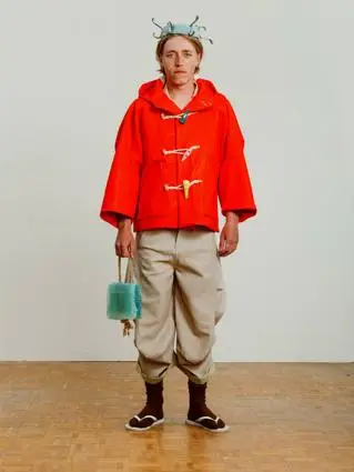 Young boy poses in red jacket, shorts a headpiece that looks like a crown