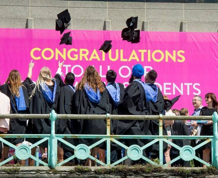 Brighton graduates through their hats in the air, facing away from the camera