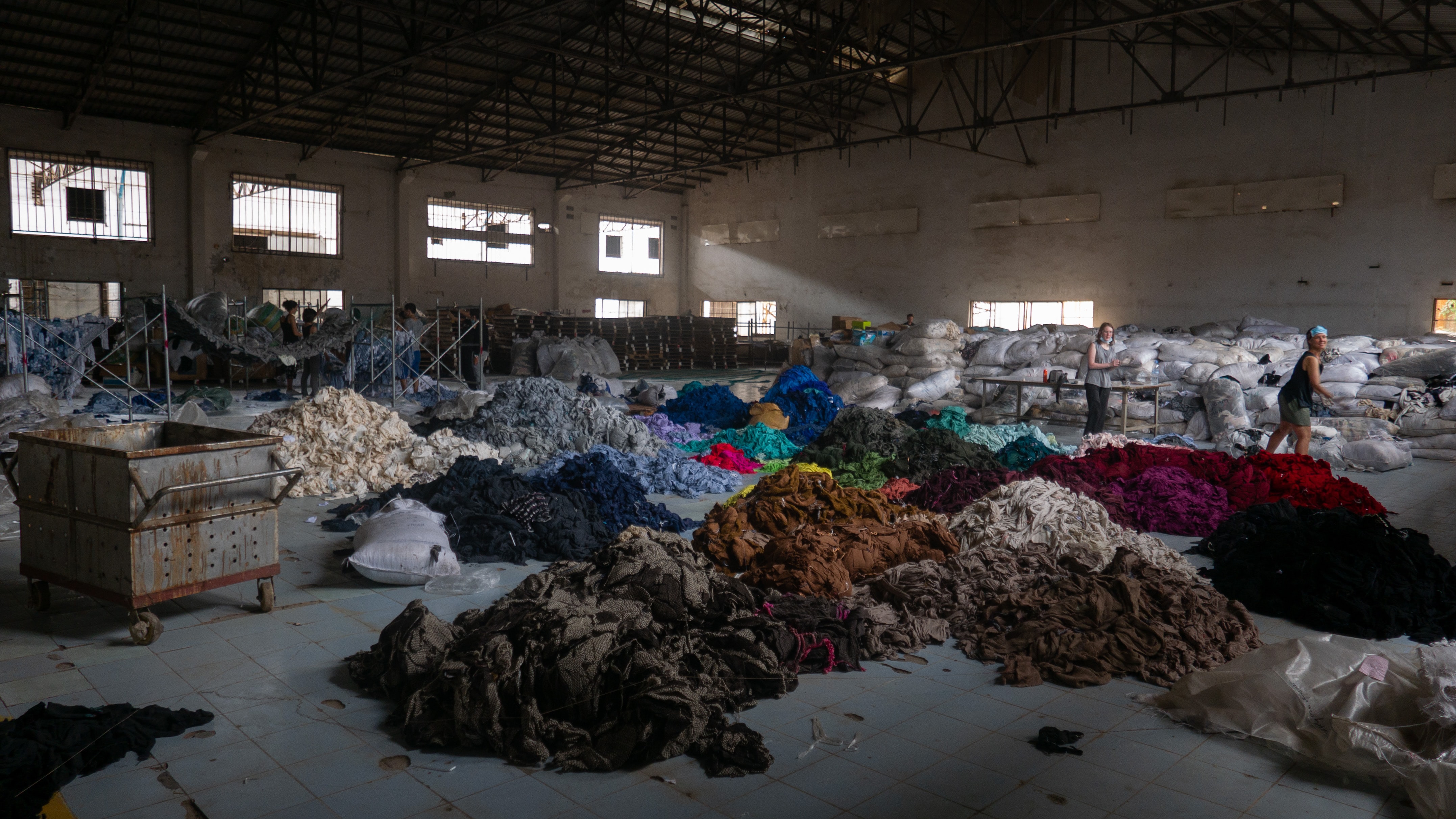 Warehouse full of piles of clothes arranged by colour