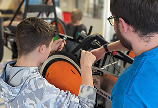 A student and an ambassador working on a car at a F24 Saturday Club