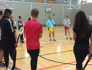 A circle of student in a gym being taught rocketball