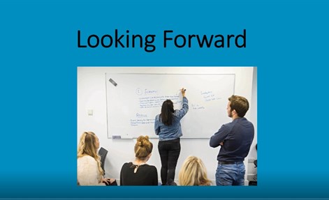 People looking at writing on a whiteboard with the words: Looking forward