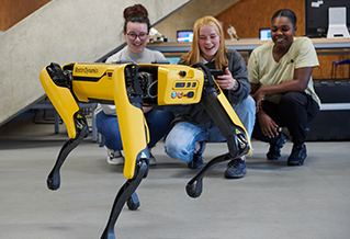 A group of students looking at a yellow Boston Dynamics robot